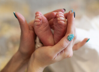 Naklejka premium close-up of mother's hands and baby's little feet.
