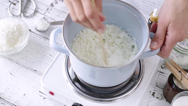 woman making candles melting soy wax in the jar