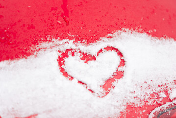 heart is painted on the snow-covered hood of a red car. Valentine's Day.	