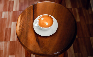 White cup of espresso coffee  on a round wooden chair at cafe