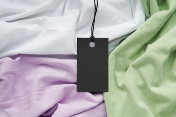 Black rectangle price tag or label mockup with string on pastel colors clothes, summer sale, discount, Black Friday concept.