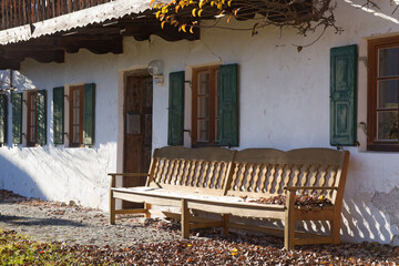 hölzerne Sitzbank in der Sonne vor einem alten Bauernhaus