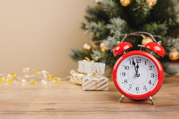 Red alarm clock and white gift boxes tied golden ribbons and bow on wooden background. Merry Christmas and Happy New Year holiday greeting card. Copy space