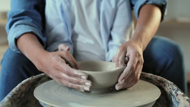 Woman teaches her son to shaping a clay pot