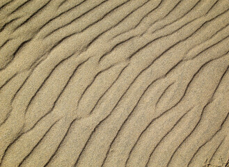Eine durch Wind und Wellen entstandene Sandtextur am Strand.
