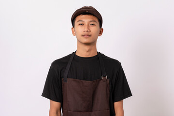 Handsome barista asian man wearing brown apron and black t-shirt isolated over white background standing with crossed arms smiling confident looking at camera