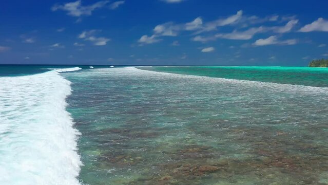 Aerial view of waves crashing on the reef in maldives local island.