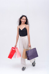 An elated asian woman holding shopping bags on both hands after going on a shopping spree. Isolated...