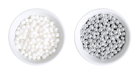 White and silver colored sugar pearls for decorating, in white bowls. Edible dragees and decorative...