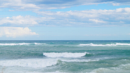 Waves surfing in the mediterranean sea. View from the beach with waves, turquoise water. Summer background.