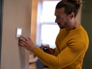 Man adjusting heating at home