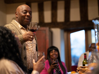 Family raising toast with red wine at Thanksgiving dinner