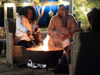 Man and woman sitting by fire pit on patio - Powered by Adobe