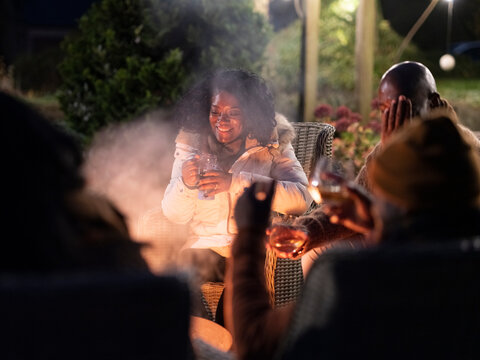 Family Sitting By Fire Pit On Patio