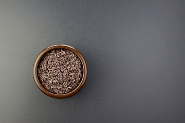 Chocolate sprinkles in a round brown bowl on a gray background. Chocolate products for decorating confectionery. 