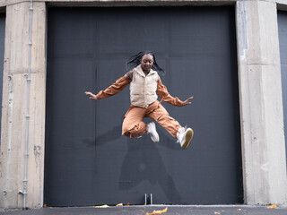 Young woman in sports clothing jumping in city
