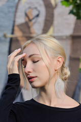 Close-up portrait of pretty blonde girl in hippie feather earrings