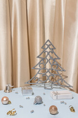 Christmas studio scene with the silver tree, gifts, baubles and ornaments on the table with satin curtain in the back