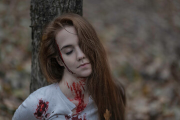 Portrait of a battered girl tied to a tree
