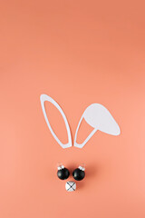 Minimalistic Christmas composition. Bunny face made from paper ears, Christmas bell and balls.