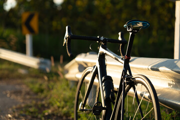 Fototapeta na wymiar Road bike parked on a beautiful road sunset, warm light with copy space.