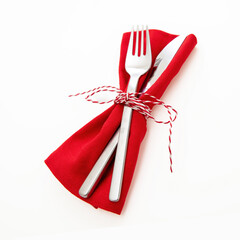 Christmas table setting, celebration dinner. Cutlery and red cloth napkin isolated on white,