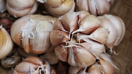 A bunch of whole garlic bulbs in a container made of bamboo.