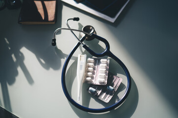 Stethoscope thermometer and pills on table in clinic