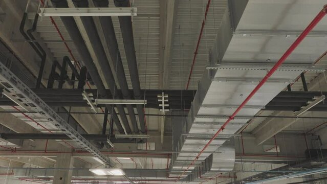 Ceiling mounted ventilation system in a large factory room with black pipelines