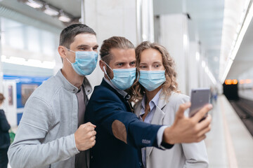 Fototapeta premium group of passengers in protective masks taking selfies in the subway.