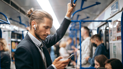 business man reading an SMS while standing in the subway car .