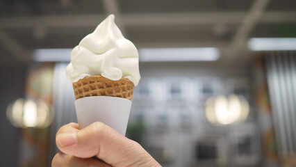 Hand is holding soft serve ice cream cone.