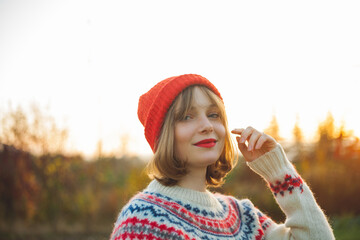 Bright winter portrait of a beautiful young woman in a knitted red hat against the background of Christmas trees. Eco christmas, winter holidays. New Year.