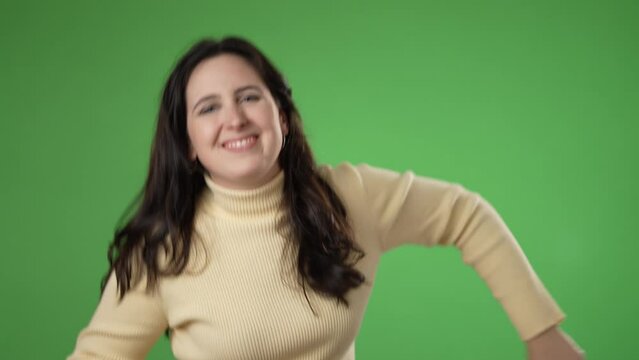 Portrait of dancing, grooving young woman 20s, enjoying music in slow motion. Attractive female surprised isolated on solid green screen background.