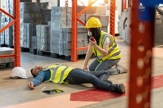 First aid by workmate. Working at warehouse. Male warehouse worker have accident.