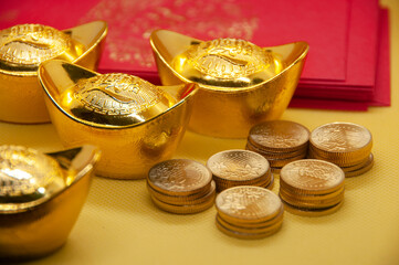 Chinese New Year packets with Chinese Gold Ingots and gold coins on yellow background. Festive season concept.