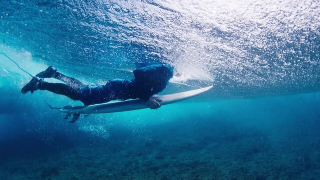 Surfer does duck dive in the clear water in the Maldives