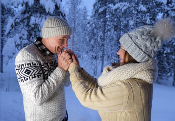 happy mature couple, man 60 years old and woman 55 years old are have fun, hugging in winter forest, early evening in park among snow-covered trees, valentine's day, enjoying nature together