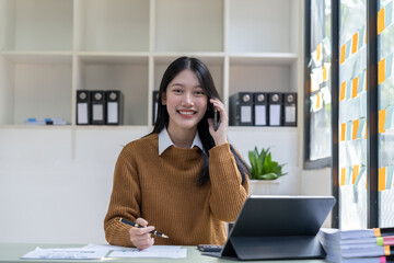 Portrait young asian businesswoman beautiful charming smiling and talking on the mobile phone in the office.