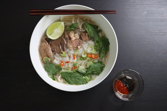 Vietnamese Instant Pho Noodle Soup with Filet and Brisket Beef, Lime, Basil, Cilantro, Green Onions, Chili, Hoisin Sauce, Sriracha Sauce - Top Down View