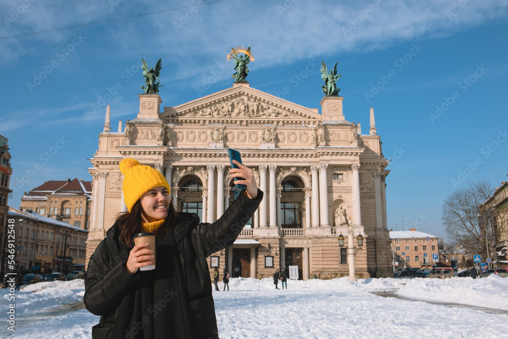 Poster woman traveler drinking coffee to go taking selfie in front of opera building