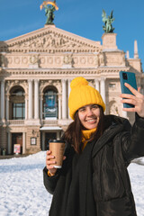 Fototapeta na wymiar woman traveler drinking coffee to go taking selfie in front of opera building