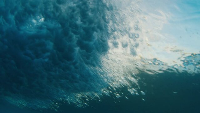 Underwater view of the ocean wave breaking on the shore in the Maldives at sunset