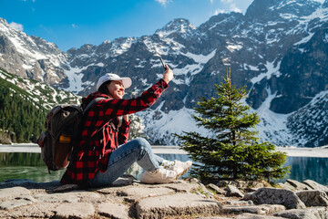 A woman is sitting on the shore of a lake. Morskie Oko, Tatras mountains. © phpetrunina14