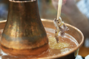 close up chopsticks pick mutton meat in traditional Chinese hot pot.