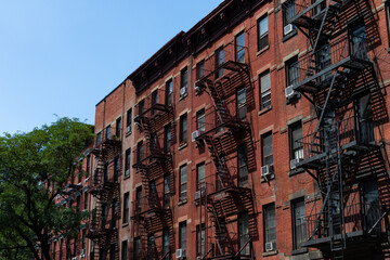 Row of Old Red Brick Apartment Buildings in Hell's Kitchen of New York City with Fire Escapes