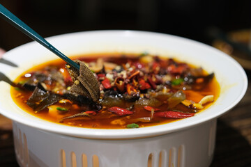 close up chopsticks picking tripe meat from a plate of spicy Sichuan cuisine - obrazy, fototapety, plakaty
