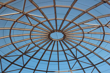 Metal frame of a dome top, interior view with blue sky outside