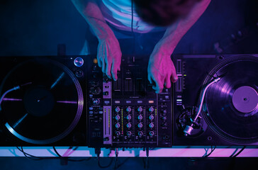 Obraz na płótnie Canvas Hip hop dj plays music on concert. Disc jockey mixing musical tracks with vinyl turntables and sound mixer in night club