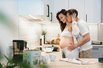 Pregnancy photo session at home, in the kitchen, in the room on the bed, by the window and in the bathroom, brushing your teeth, putting your hands on your tummy and making cheesecakes from flour